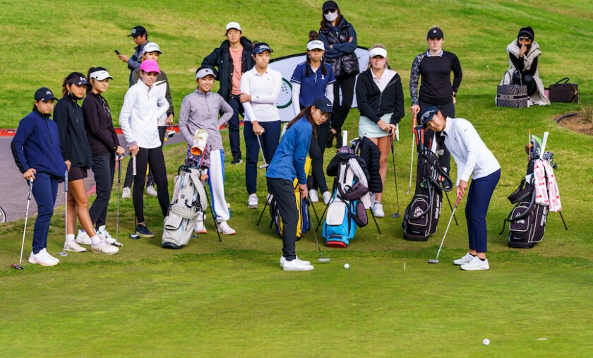 Young junior golfers watch on
