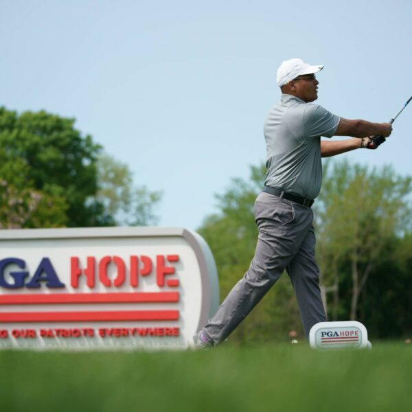 Golfer tees off next to PGA HOPE advertising board