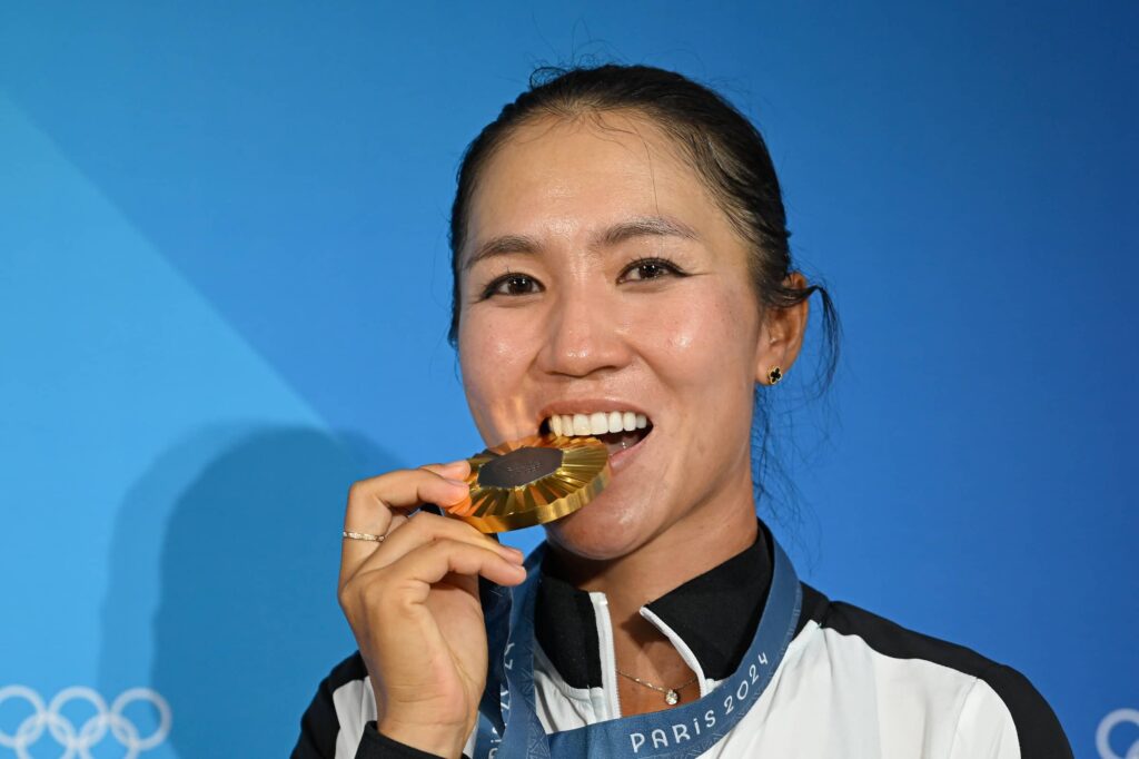 Lydia Ko of Team New Zealand, gold medalist, bites her medal after the final round of the 2024 Paris Olympics at Le Golf National